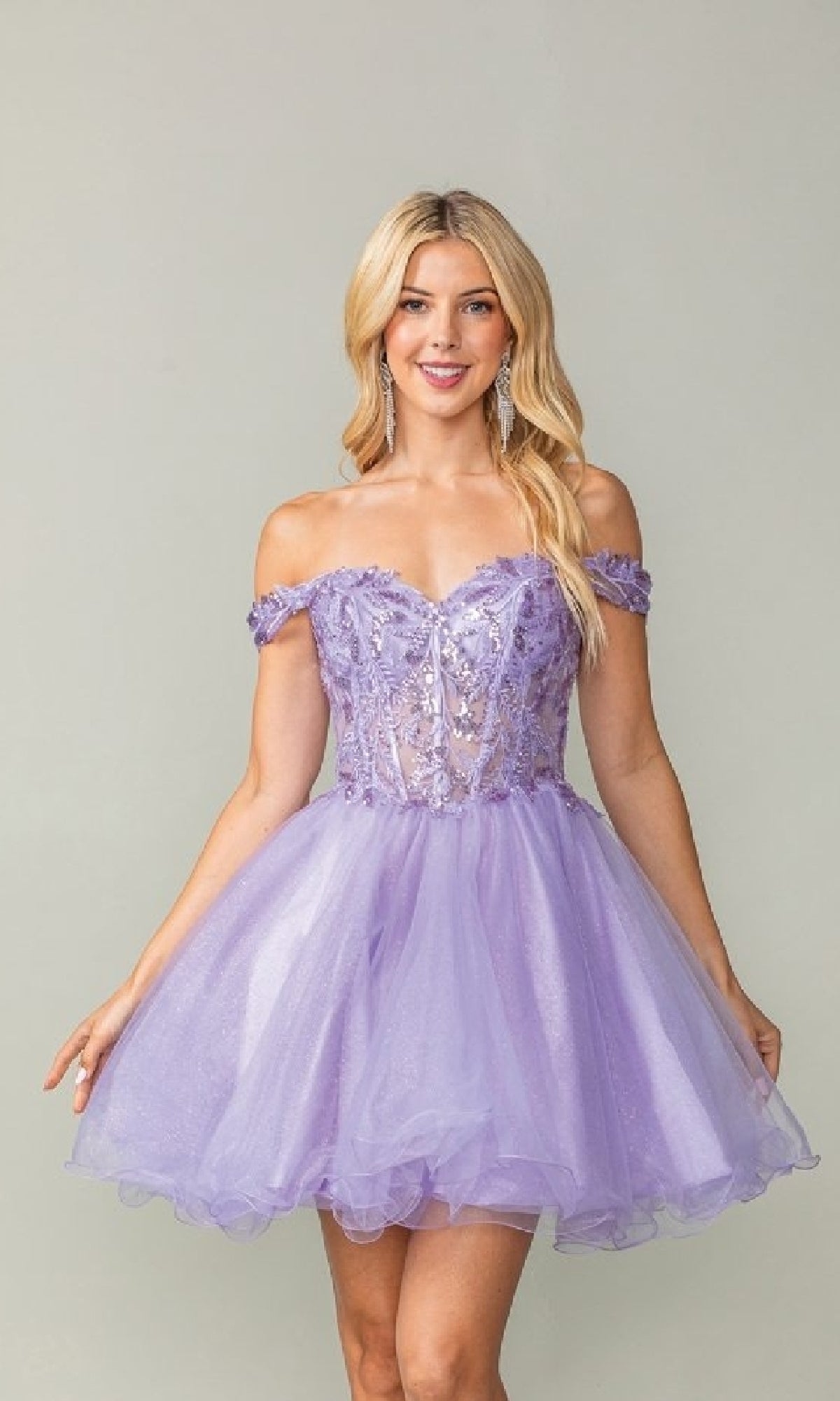 Woman wearing a lilac purple off-shoulder short poofy dress with sequin details on a plain background